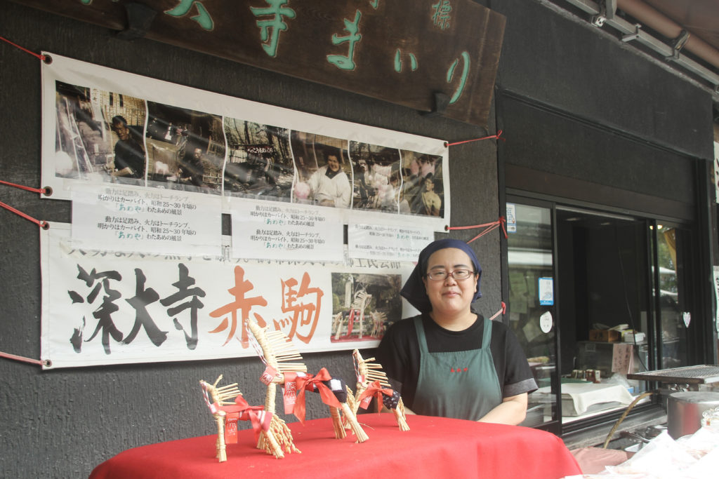 深大寺まいりの看板の前に立つ女性。